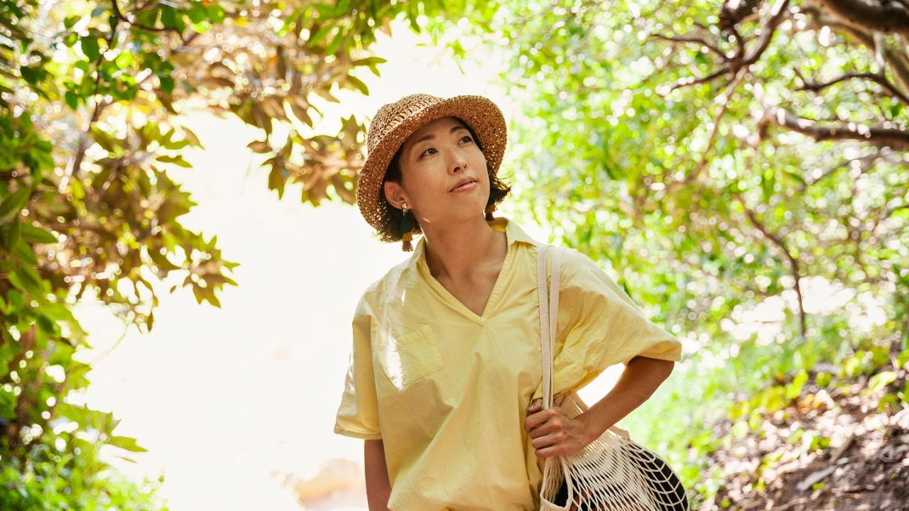 Woman in bright yellow shirt walking through a forest