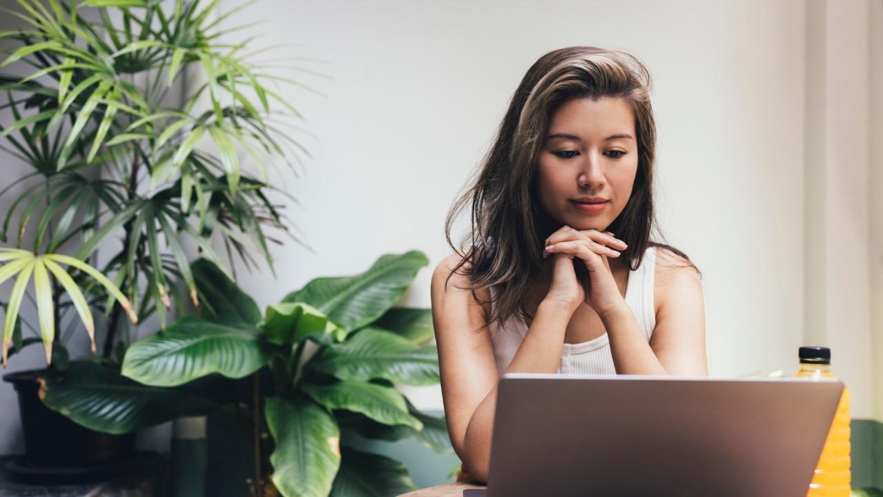 A young Asian woman joining in a video call on her laptop computer.